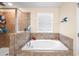 Elegant bathroom featuring a soaking tub with tile surround and a glass-enclosed shower at 14095 Tropical Kingbird Way, Riverview, FL 33579