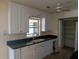 A kitchen featuring white cabinets, a black countertop, and stainless steel sink beneath the window at 155 Summerset Dr, Punta Gorda, FL 33982