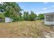 A large backyard, featuring a flat grassy area and mature trees, next to a home's screened patio at 5629 36Th N Ave, St Petersburg, FL 33710