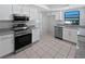 Modern kitchen features stainless appliances, granite counters, white cabinets, and tile flooring at 6623 Baybrooks Cir, Temple Terrace, FL 33617