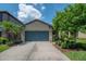 Charming single-story home with a well-maintained lawn, mature trees, and a spacious driveway leading to a blue garage door at 8410 Red Spruce Ave, Riverview, FL 33578
