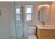 Stylish bathroom with a glass-enclosed shower, sleek vanity, round mirror, and marble-patterned walls at 1933 Oregon Trl, Englewood, FL 34224