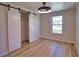 Cozy bedroom with wood floors, modern lighting, sliding closet door, and a bright window at 1933 Oregon Trl, Englewood, FL 34224