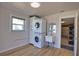 Functional laundry room with stacked washer/dryer, utility sink, storage, and wood-look flooring at 1933 Oregon Trl, Englewood, FL 34224
