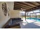Relaxing covered patio with comfy couch overlooks the screened pool and water at 1933 Oregon Trl, Englewood, FL 34224