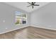 Neutral bedroom featuring wood-look floors, a ceiling fan, and a large window with blinds at 7511 Savannah Ln, Tampa, FL 33637