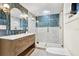Beautiful bathroom features blue accent wall, modern vanity, lighting fixtures and glass enclosed shower with matching blue tile at 203 Driftwood W Dr, Palm Harbor, FL 34683