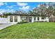 A modern house with a green lawn and a well-maintained garden in the front yard at 203 Driftwood W Dr, Palm Harbor, FL 34683