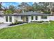 Charming single-story home featuring a well-manicured lawn, modern design, and a welcoming front entrance at 203 Driftwood W Dr, Palm Harbor, FL 34683