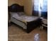 Cozy bedroom with a wooden bed frame, patterned linens, and tile flooring at 6718 Runningwoods Dr, Tampa, FL 33634