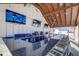 Stylish outdoor bar area with TVs, granite countertops, bar stools, and modern lighting fixtures at 9188 Forge Breeze Loop, Wesley Chapel, FL 33545