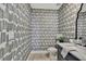 Chic half bathroom with patterned wallpaper, modern fixtures, and a marble countertop at 9188 Forge Breeze Loop, Wesley Chapel, FL 33545