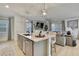 Stylish kitchen island with sink, seating, and pendant lighting, open to the living room at 9188 Forge Breeze Loop, Wesley Chapel, FL 33545