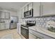 Modern kitchen featuring stainless steel appliances, white cabinets, and patterned backsplash at 9188 Forge Breeze Loop, Wesley Chapel, FL 33545