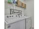Clean laundry room with modern washer, dryer, shelving and a laundry sign at 9188 Forge Breeze Loop, Wesley Chapel, FL 33545