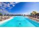 Expansive resort-style pool featuring crystal-clear water, lounge chairs, and umbrellas under a sunny sky at 9188 Forge Breeze Loop, Wesley Chapel, FL 33545