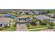 Aerial view of a landscaped home with a tile roof, solar panels, attached garage, palm trees, and a serene pond nearby at 29043 Picana Ln, Wesley Chapel, FL 33543