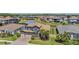Aerial view of a landscaped home with a tile roof, attached garage, palm trees, and a serene pond nearby at 29043 Picana Ln, Wesley Chapel, FL 33543