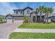 Inviting home exterior featuring lush greenery, manicured lawn, and a paver driveway at 29043 Picana Ln, Wesley Chapel, FL 33543