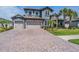Beautiful home featuring a stone facade, tile roof, three-car garage, brick driveway, and well-manicured landscaping at 29043 Picana Ln, Wesley Chapel, FL 33543