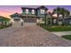 Beautiful home featuring a stone facade, tile roof, three-car garage, brick driveway, and well-manicured landscaping at 29043 Picana Ln, Wesley Chapel, FL 33543