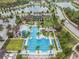 Aerial view of a luxurious community pool and clubhouse, surrounded by palm trees and ample lounge chairs at 29043 Picana Ln, Wesley Chapel, FL 33543