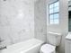 Bright bathroom with white marble-style tiled walls, white fixtures, and a window at 8231 Riverside Ne Dr, St Petersburg, FL 33702