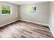 Bright bedroom featuring wood-look flooring and two windows for natural light at 1736 Taylor Lake Pl, Largo, FL 33778