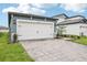 Spacious garage with brick paver driveway and manicured landscaping at 1828 Brekey Way, Zephyrhills, FL 33541