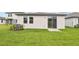 The backyard features a well manicured lawn, a privacy fence, an air conditioning unit and a sliding glass door at 1847 Brekey Way, Zephyrhills, FL 33541