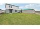 Wide backyard with green lawn, features a sliding door and growing tree at 1855 Brekey Way, Zephyrhills, FL 33541