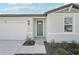 Close up of the front entry featuring a green front door, landscaping, and two-car garage at 7728 Gilchrist Springs Dr, Parrish, FL 34219