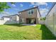 Back exterior showcasing a well-kept lawn, private fence, and a stone-paved patio area at 13083 Burns Dr, Odessa, FL 33556