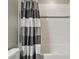 Bright bathroom featuring a modern tub, white tile, and a stylish gray and white striped shower curtain at 13083 Burns Dr, Odessa, FL 33556