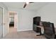 Well-lit bedroom with ceiling fan, open doorway, carpet flooring, and a functional workspace at 13083 Burns Dr, Odessa, FL 33556