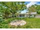 Backyard with fire pit, large tree, lush lawn, and screened-in porch at 709 S Himes Ave, Tampa, FL 33609