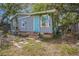 Exterior view of the back of house showing a blue door, window and overgrown yard at 9307 N Oakleaf Ave, Tampa, FL 33612
