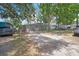 Charming single-story home with a large gravel driveway, mature trees, and a light blue front door at 9307 N Oakleaf Ave, Tampa, FL 33612