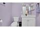 Light purple bathroom featuring a toilet, sink, mirror, and black trash bin at 5016 W Lancaster St # 00, Tampa, FL 33616