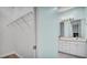 Bright bathroom featuring double sinks, white cabinets, and open closet with storage shelves at 5016 W Lancaster St # 00, Tampa, FL 33616