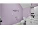 Light purple bathroom featuring a toilet, sink, mirror, and towel rack at 5016 W Lancaster St # 00, Tampa, FL 33616
