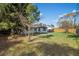 A large backyard with mature trees and green grass provides a peaceful setting at 1073 Kenwood Dr, Dunedin, FL 34698