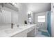 Modern bathroom with dual sinks, white marble countertop, updated fixtures, and a blue shower curtain at 1073 Kenwood Dr, Dunedin, FL 34698