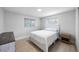 A bright bedroom features wood floors, a white bed and wooden night stand at 1073 Kenwood Dr, Dunedin, FL 34698
