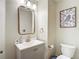 Well-lit half bathroom featuring a vanity with gray cabinets, modern fixtures, and toilet at 18109 Kara Ct, Tampa, FL 33647