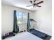 Carpeted bedroom with a ceiling fan, a window with views of green trees, and home workout equipment at 18109 Kara Ct, Tampa, FL 33647