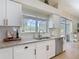 Well-lit kitchen with granite countertops, white cabinets, and a stainless steel dishwasher and sink at 18109 Kara Ct, Tampa, FL 33647