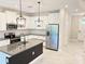 Modern kitchen boasts white cabinets, stainless steel appliances, granite countertops and island with stylish pendant lighting at 18875 Noble Caspian Dr, Lutz, FL 33558