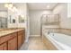 Large bathroom featuring dual sinks, granite countertops, soaking tub, and glass enclosed shower at 11621 Ashton Field Ave, Riverview, FL 33579