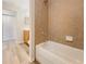 Bright bathroom featuring a bathtub with tile surround and a wood-look floor at 13210 Essman Ave, Port Charlotte, FL 33953